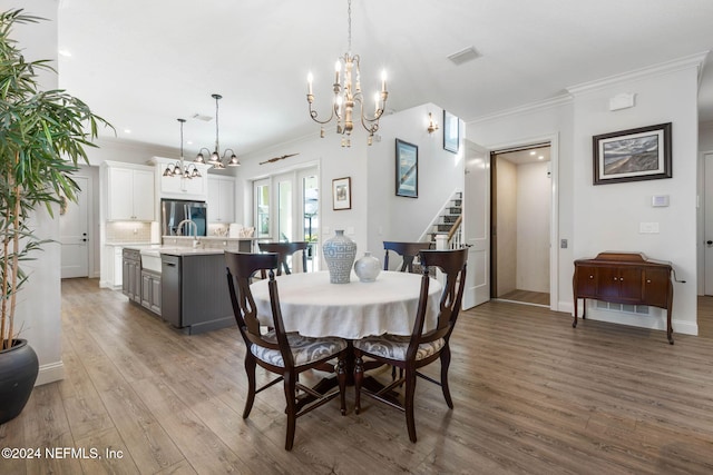 dining space featuring a notable chandelier, sink, wood-type flooring, and crown molding