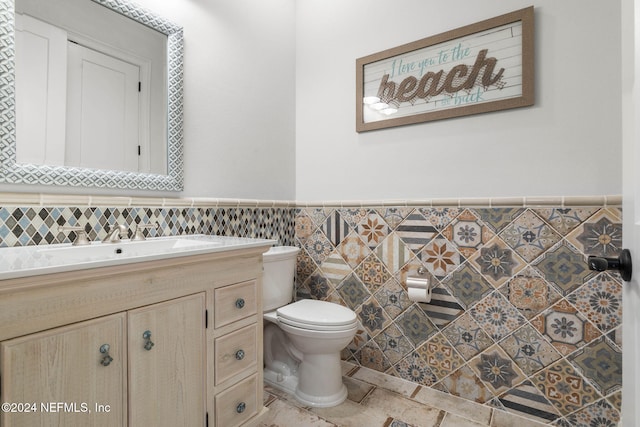 bathroom featuring vanity, tile walls, and toilet