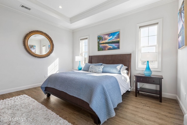 bedroom featuring a raised ceiling, crown molding, and wood-type flooring