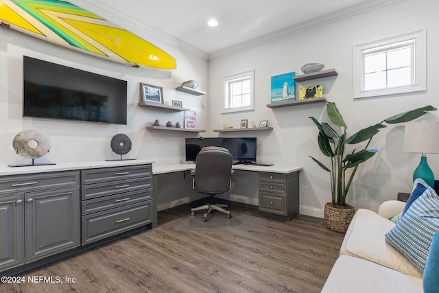 office area with built in desk, ornamental molding, and dark wood-type flooring