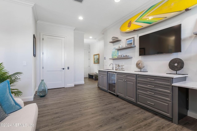 bar with dark hardwood / wood-style flooring, ornamental molding, sink, and beverage cooler