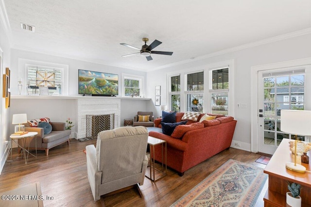 living room featuring dark hardwood / wood-style flooring, ceiling fan, a fireplace, and ornamental molding