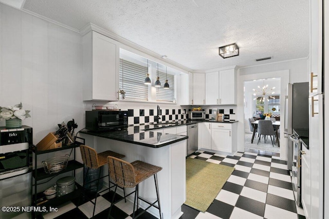 kitchen with a kitchen breakfast bar, kitchen peninsula, a wealth of natural light, and white cabinets