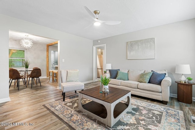 living room with wood-type flooring and ceiling fan with notable chandelier