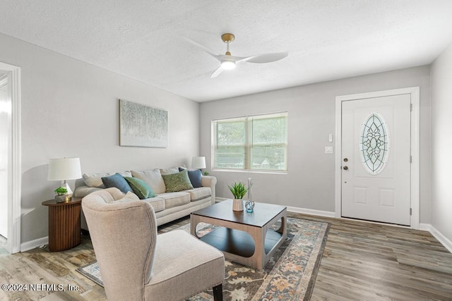 living room featuring ceiling fan, light wood-type flooring, and a textured ceiling