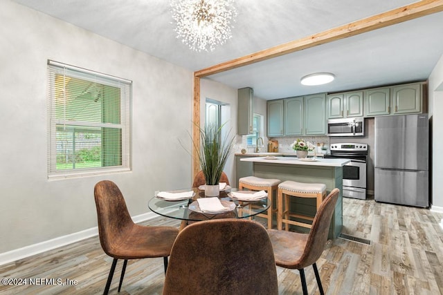 dining area with beam ceiling, a chandelier, sink, and light hardwood / wood-style floors