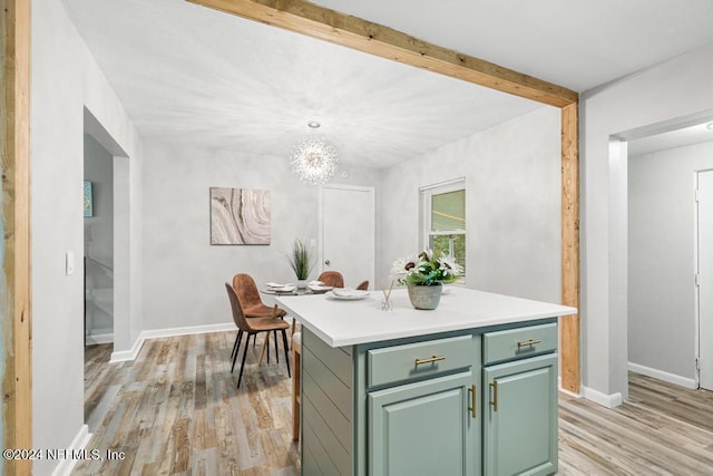 kitchen with an inviting chandelier, green cabinetry, light wood-type flooring, decorative light fixtures, and a kitchen island