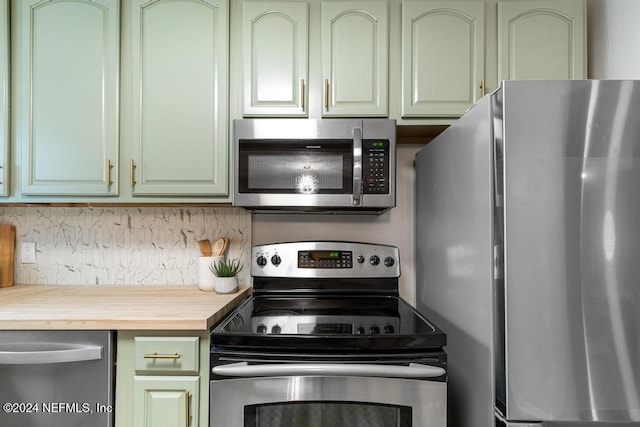 kitchen featuring appliances with stainless steel finishes, backsplash, butcher block countertops, and green cabinets