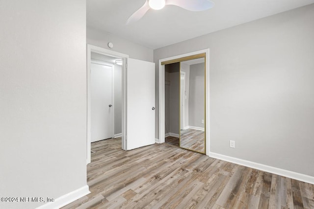 unfurnished bedroom featuring ceiling fan, a closet, and light hardwood / wood-style flooring