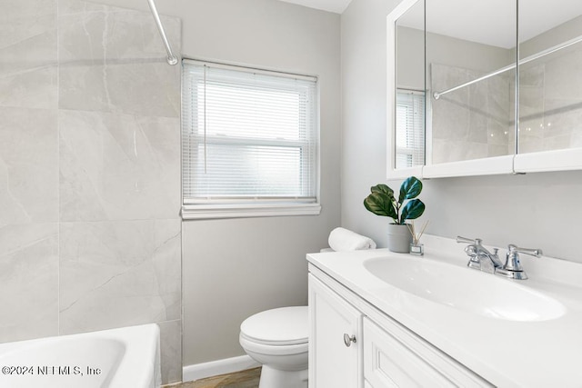 full bathroom with tiled shower / bath, vanity, and toilet