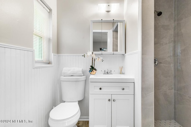 bathroom with a tile shower, vanity, and toilet