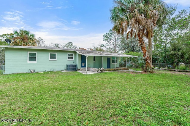 rear view of property featuring central AC and a lawn