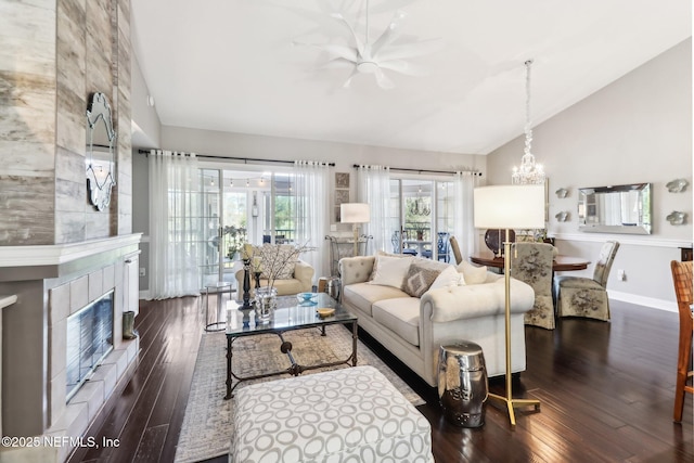 living room featuring a tile fireplace, dark hardwood / wood-style flooring, a chandelier, and lofted ceiling