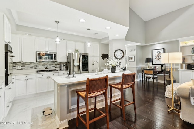 kitchen featuring pendant lighting, a center island with sink, a breakfast bar area, white cabinetry, and stainless steel appliances