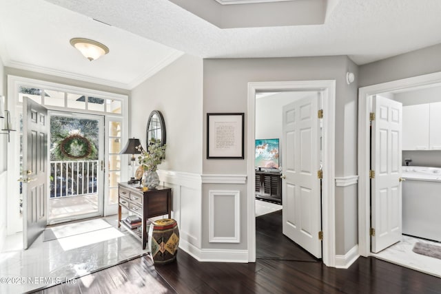 foyer featuring washer / dryer, a textured ceiling, ornamental molding, and dark wood-type flooring