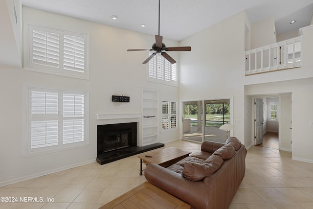 living room featuring a high ceiling, light tile patterned floors, and ceiling fan