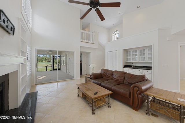 living room with a towering ceiling, ceiling fan, and light tile patterned flooring