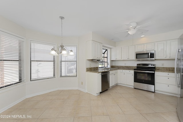 kitchen with stainless steel appliances, sink, pendant lighting, white cabinets, and light tile patterned flooring