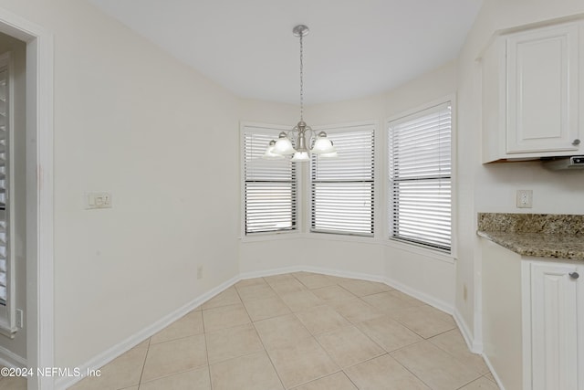 unfurnished dining area featuring light tile patterned flooring and a chandelier