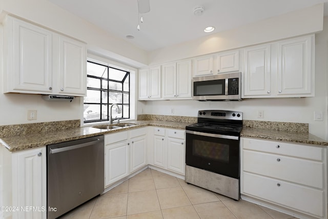 kitchen with white cabinetry, sink, dark stone countertops, light tile patterned floors, and appliances with stainless steel finishes