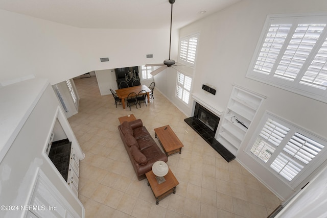 living room with ceiling fan, a fireplace, and a high ceiling