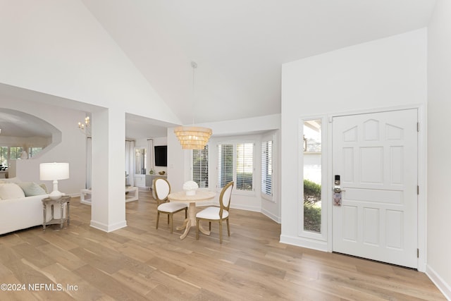 foyer entrance featuring light hardwood / wood-style floors, high vaulted ceiling, and a notable chandelier