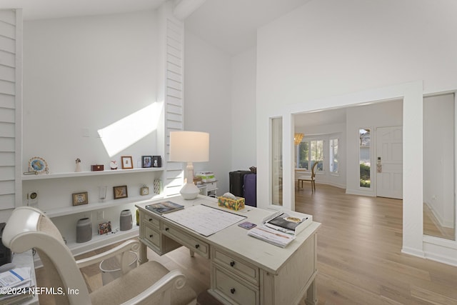 office featuring a skylight, built in features, high vaulted ceiling, and light hardwood / wood-style floors