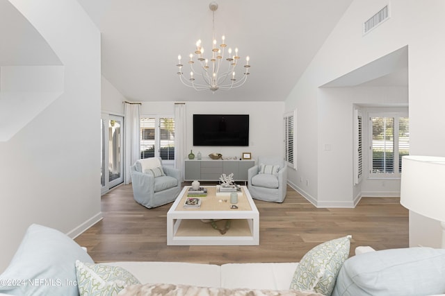 living room with a notable chandelier, wood-type flooring, and lofted ceiling