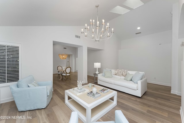 living room with hardwood / wood-style floors, a notable chandelier, and vaulted ceiling