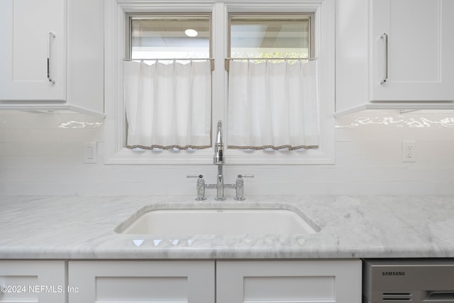 details featuring decorative backsplash, light stone counters, white cabinetry, and sink