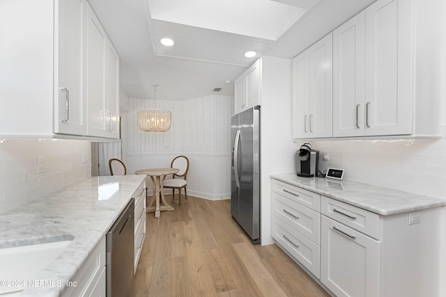 kitchen featuring white cabinetry, hanging light fixtures, light wood-type flooring, and appliances with stainless steel finishes