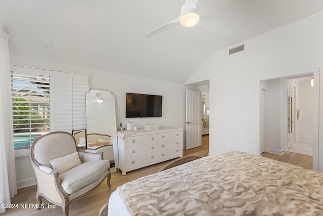 bedroom with ceiling fan, vaulted ceiling, connected bathroom, and light hardwood / wood-style flooring