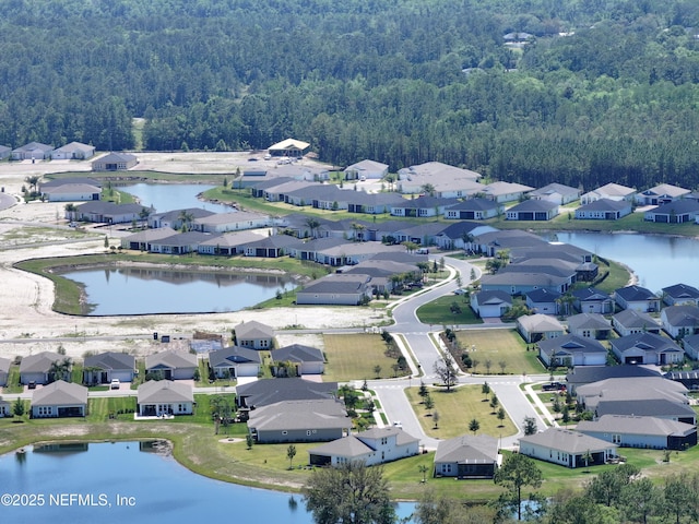 birds eye view of property featuring a water view, a wooded view, and a residential view