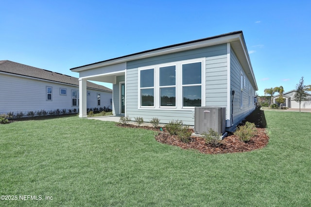 rear view of property featuring a yard and central AC unit