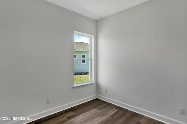 empty room with a wealth of natural light, dark wood-style flooring, and baseboards