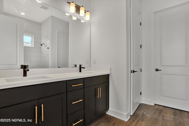 full bath with visible vents, a tile shower, a sink, and wood finished floors