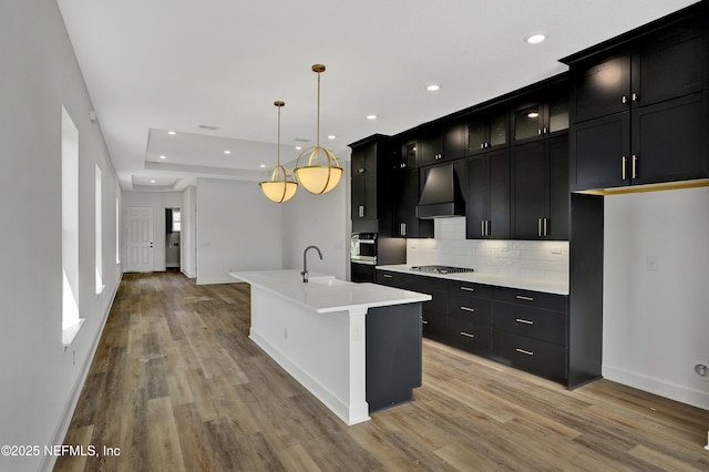 kitchen with dark cabinetry, extractor fan, a sink, and appliances with stainless steel finishes