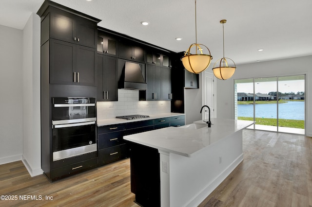 kitchen with stainless steel double oven, a sink, gas stovetop, light wood-style floors, and custom range hood