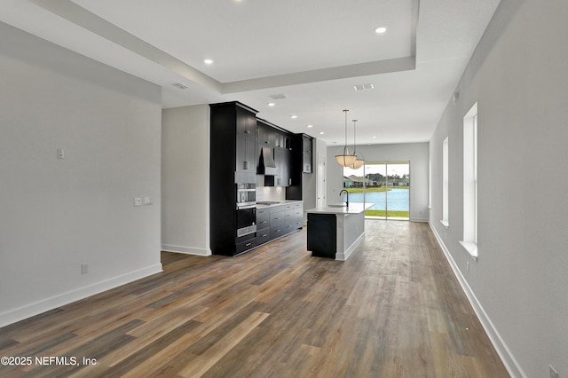 kitchen with dark wood-type flooring, baseboards, light countertops, and dark cabinetry