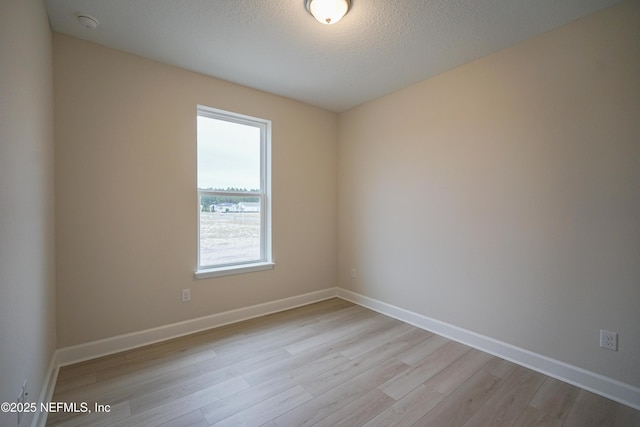 unfurnished room with a textured ceiling and light wood-type flooring