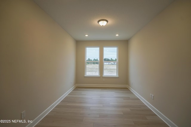 empty room featuring light wood finished floors, baseboards, a textured ceiling, and recessed lighting