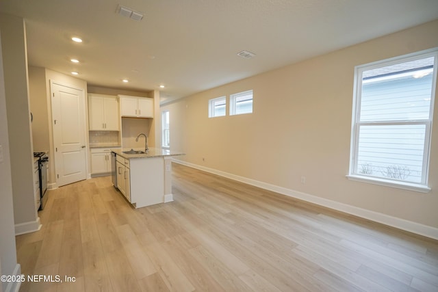 kitchen with white cabinets, sink, an island with sink, light hardwood / wood-style floors, and stainless steel appliances