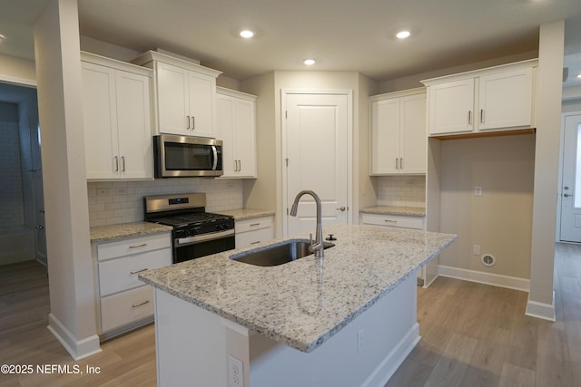 kitchen with stainless steel appliances, light wood-style floors, white cabinetry, and a sink