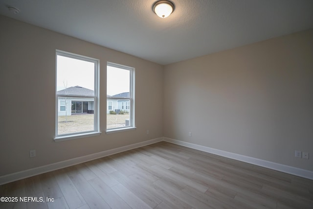 unfurnished room with a textured ceiling, baseboards, and wood finished floors