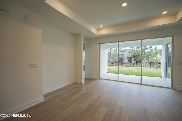 unfurnished room with a raised ceiling and hardwood / wood-style flooring