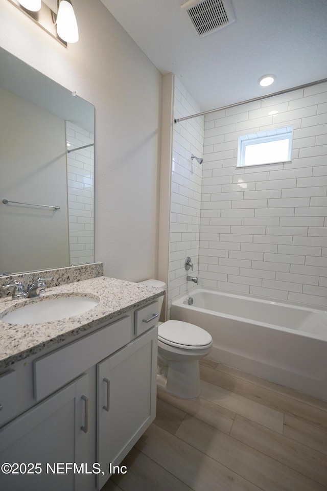 full bathroom with toilet, vanity, and tiled shower / bath