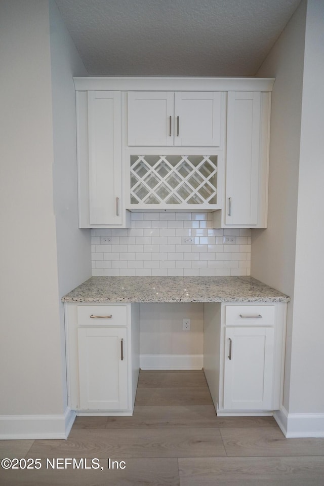 kitchen with white cabinets, built in desk, and tasteful backsplash