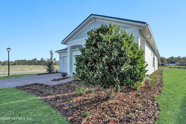 view of home's exterior with an attached garage, a lawn, and decorative driveway