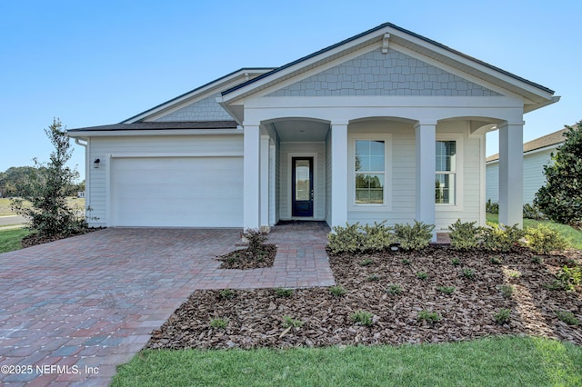 view of front of house with covered porch, decorative driveway, and an attached garage