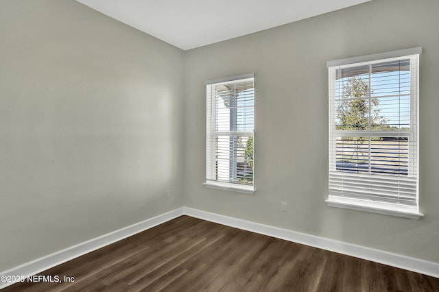 empty room with dark wood-style flooring and baseboards